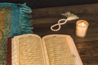 prayer-beads-candle-near-religious-book